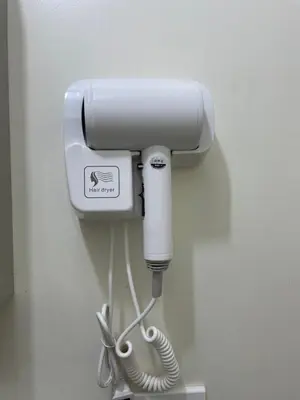 a white hair dryer hanging on a wall at Satori Residences in Manila