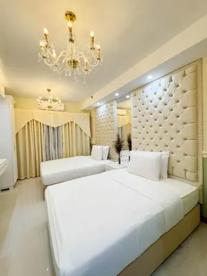 two beds in a hotel room with a chandelier at Homefort Twin Bed Suite - Red Residences Makati 2202 in Manila