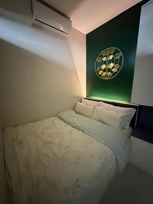 a small bed in a room with a green wall at Modern and Cozy Suite at Shore Residences in Manila
