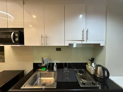 a kitchen with a sink and white cabinets at Modern and Cozy Suite at Shore Residences in Manila