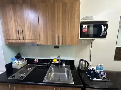 a kitchen with a sink and a microwave at Modern and Cozy Suite at Shore Residences in Manila
