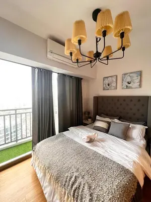 a bedroom with a large bed with a chandelier at Staycation in Mandaluyong near Makati and BGC in Manila