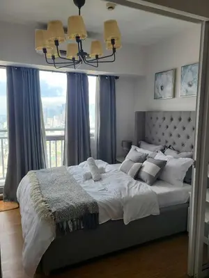 a bedroom with a large bed with a chandelier at Staycation in Mandaluyong near Makati and BGC in Manila