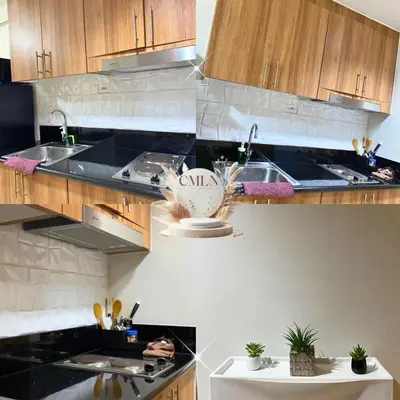 a kitchen with black counter tops and wooden cabinets at cmln staycation metro manila in Manila