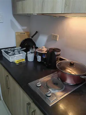 a kitchen counter with a stove with pots and pans at lhey's staycation in Manila