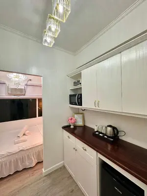a room with a bed and a kitchen with white cabinets at Studio Two Condominium, Alabang - GOLD FIBER WI-FI -NETFLIX READY in Manila