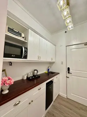 a kitchen with white cabinets and a counter top at Studio Two Condominium, Alabang - GOLD FIBER WI-FI -NETFLIX READY in Manila
