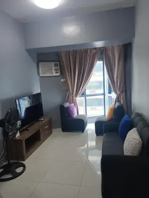 a living room with two blue couches and a television at FamilyRoom 1 bedroom in Manila