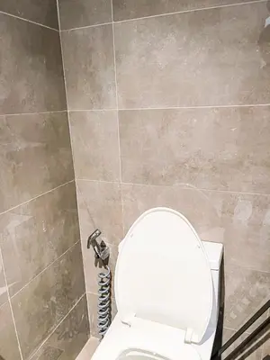 a bathroom with a toilet and a tiled wall at Lovely Penthouse across City of Dreams, Airport in Manila