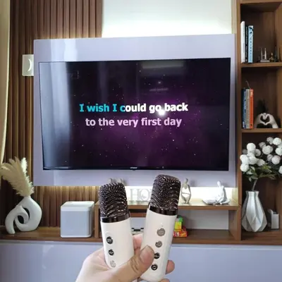 a person holding two microphones in front of a tv at Field Residence Cozy Condo In Paranaque in Manila