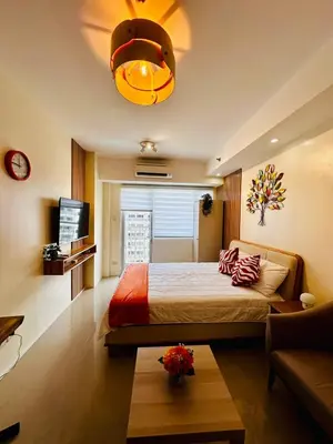 a bedroom with a bed and a tv and a table at 1232A Near MOA and Airport Pool View Balcony in Manila