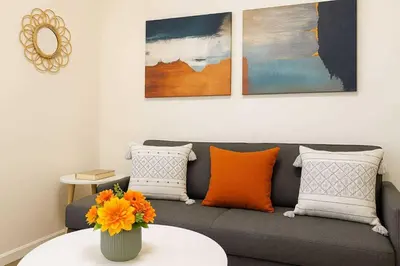 a living room with a gray couch with orange pillows at 729A Near MOA and Airport PoolView Balcony in Manila