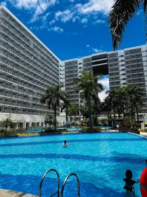 a person in a swimming pool in front of a large building at 729A Near MOA and Airport PoolView Balcony in Manila
