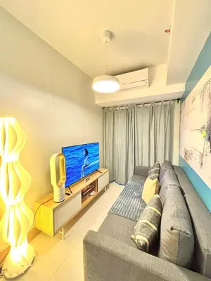 a living room with a couch and a flat screen tv at Haven At Home - Staycation at Shore Residences in Manila