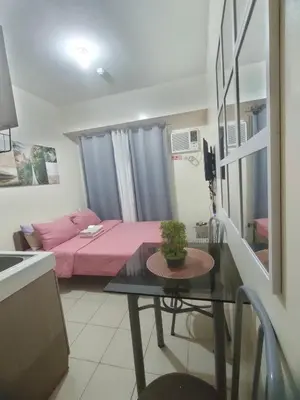 a small room with a pink bed and a table at Gaby's Condotel in Manila