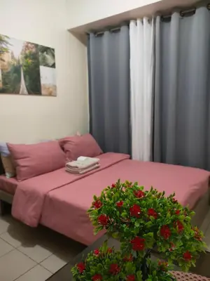 a bedroom with a bed with pink sheets and red flowers at Gaby's Condotel in Manila