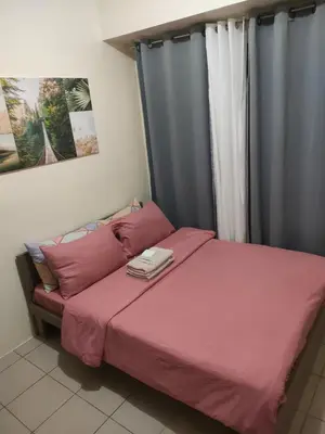 a bedroom with a bed with pink sheets and a window at Gaby's Condotel in Manila