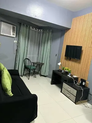 a living room with a black couch and a tv at Family Budget Room in Manila