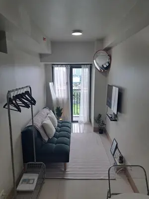 a living room with a blue couch and a window at Yutori Haus at Shore 3 Tower 2 near Mall of Asia Pasay City in Manila