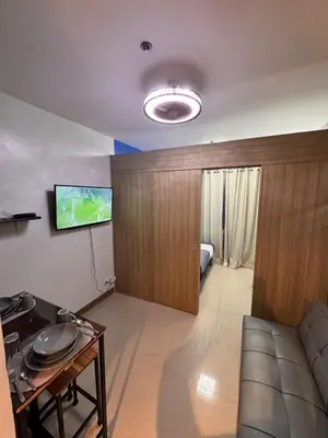 a living room with a couch and a tv on a wall at Iris Suites in Manila