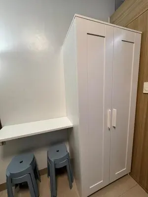 a white cabinet with two blue stools in a room at Iris Suites in Manila