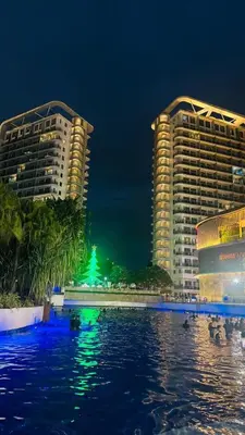 two tall buildings next to a body of water at night at Jules Cozy StayCay II in Manila
