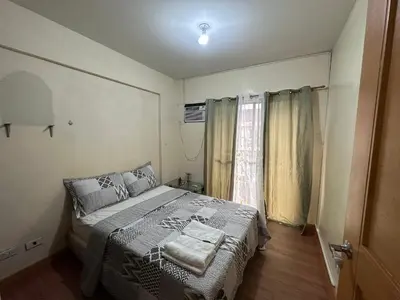a small bedroom with a bed and a window at Staycation in Taguig in Manila