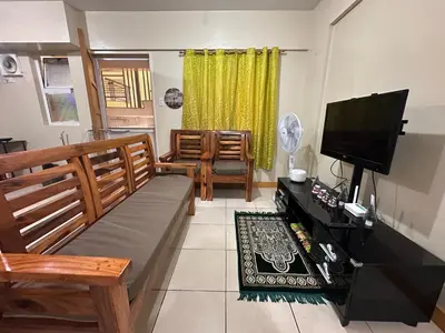 a living room with a couch and a flat screen tv at Staycation in Taguig in Manila