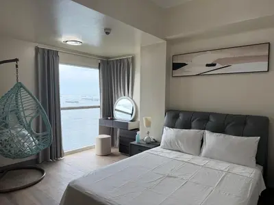 a bedroom with a bed and a large window at Luxurious Style Apartment cross to Okada and near City of Dreams, Solaire, MOA, and Airport in Manila