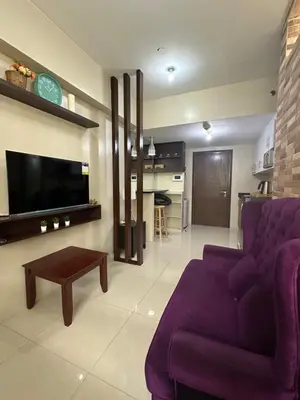 a living room with a purple couch and a tv at One Palm Tree by Melba STUDIO TYPE in Manila