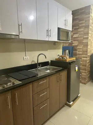 a kitchen with wooden cabinets and a sink and a stove at One Palm Tree by Melba STUDIO TYPE in Manila