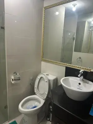 a bathroom with a toilet and a sink and a mirror at One Palm Tree by Melba STUDIO TYPE in Manila