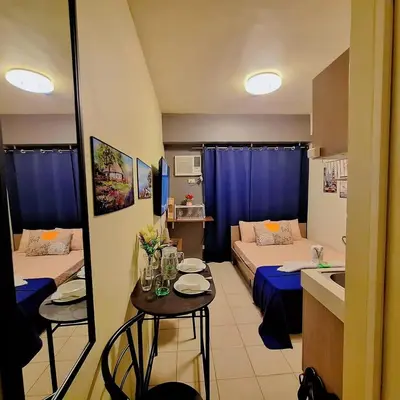 a small room with two beds and a small table with a kitchen at G and A CONDOTELS in Manila