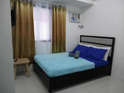 a bedroom with a bed with blue sheets and a window at Cozy Studio typeunit in Manila