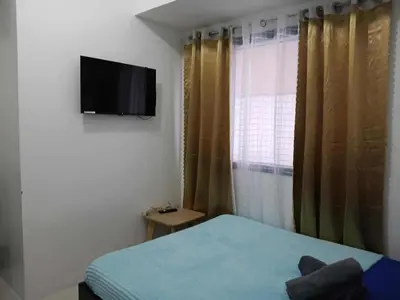 a bedroom with a bed and a television on the wall at Cozy Studio typeunit in Manila