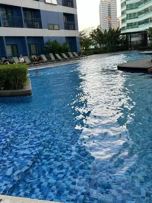a large swimming pool with blue tiles in front of a building at 2 Bed Suite at Air Residences Condo, Ayala Ave Makati in Manila