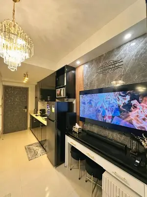 a living room with a large screen tv and a kitchen at Château Zen&Kat in Manila