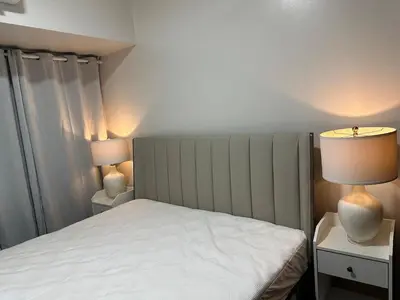 a bedroom with a bed and two lamps on tables at A King-size bed at Air Residences Condo, Ayala Ave, Makati in Manila