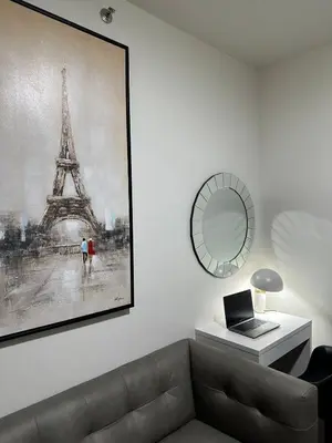 a living room with a couch and a picture of the eiffel tower at A King-size bed at Air Residences Condo, Ayala Ave, Makati in Manila