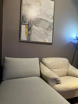 a living room with a white chair and a painting at Air Residences Apartment, Ayala Avenue Makati in Manila