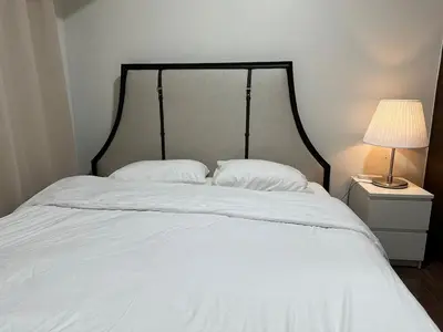 a white bed with two pillows and a lamp on a night stand at King size bed at Air Residences Condo, Ayala Ave, Makati in Manila