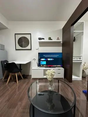 a living room with a glass table and a television at King size bed at Air Residences Condo, Ayala Ave, Makati in Manila