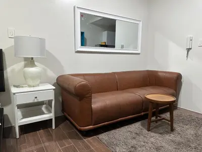 a brown leather couch in a living room with a mirror at Suite at Air Residences Condo, Ayala Ave Makati in Manila