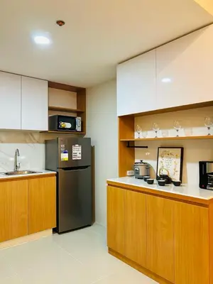 a kitchen with wooden cabinets and a black refrigerator at Kate's Haven Jazz Residences Makati, Manila in Manila
