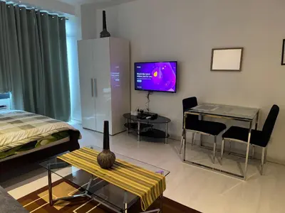 a living room with a bed and a tv on the wall at Gramercy Residences Studio With Balcony City View in Manila