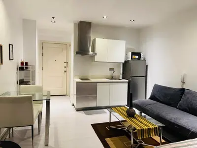 a kitchen and living room with a couch and a table at Gramercy Residences Studio With Balcony City View in Manila