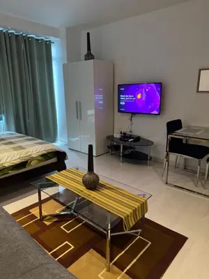 a living room with a bed and a tv and a table at Gramercy Residences Studio With Balcony City View in Manila
