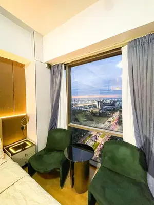 a bedroom with two green chairs and a large window at Luxury Condo in Manila Bay near US Embassy in Manila