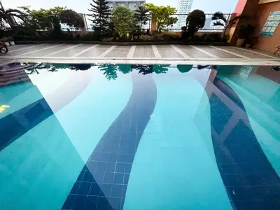 a blue tile swimming pool with its reflection in the water at Luxury Condo in Manila Bay near US Embassy in Manila