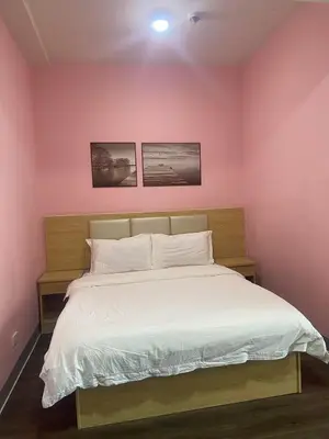 a pink bedroom with a bed with white sheets at La Chicka Staycation in Coast Residences in Manila
